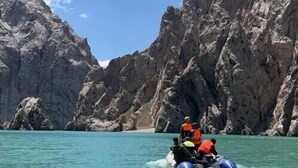 Un grupo de personas en una embarcación en un mar azul y transparente, con acantilados rocosos al fondo.