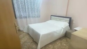 A room with a bed, a nightstand, and a window with curtains. - Sea View Apartment in Durres Albania (Durrës)