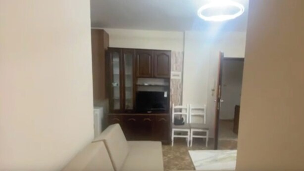 A living room with a sofa, a dining table with chairs, and a kitchen area with cabinets and a microwave. - Sea View Apartment in Durres Albania (Durrës)