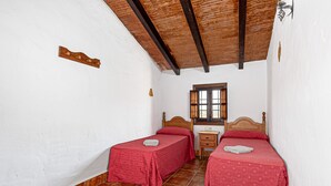 Une chambre avec deux lits, une tête de lit en bois, une petite table et une fenêtre.