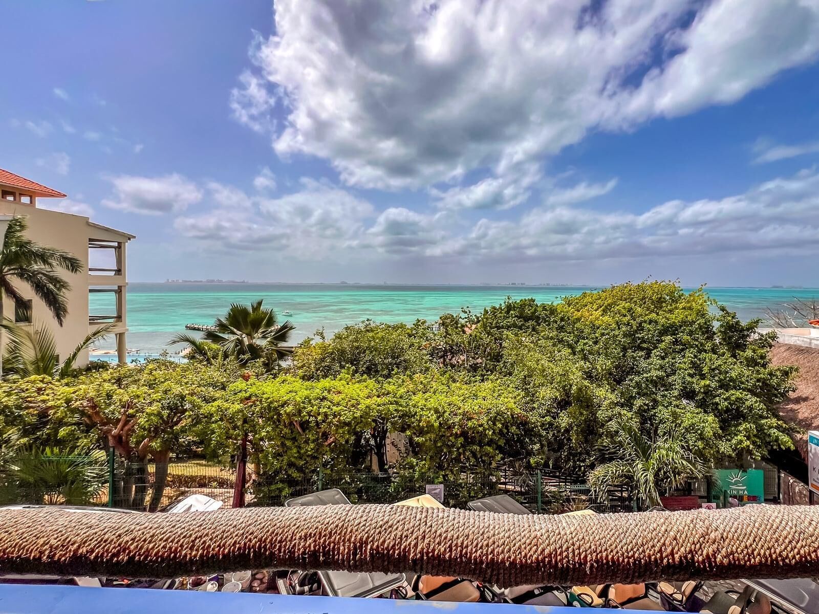 A coastal view with a clear sky, turquoise sea, and lush greenery.
