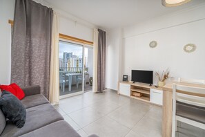 A modern living room with a sofa, TV, and a view of the city.