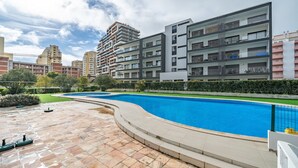 A modern apartment complex with a swimming pool, a well-maintained lawn, and a clear sky. - Apartment 'Solmonte' with Shared Pool, Wi-Fi and Air Conditioning (Portimão)
