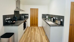 A modern kitchen with a central island, wooden flooring, and a built-in microwave. - Viewforth Studio No.4 (Fort William)