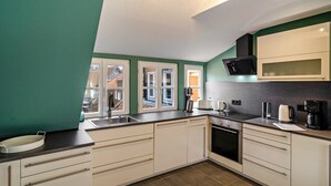 Une cuisine moderne dotée d’une grande fenêtre, d’un four encastré et de meubles de rangement blancs.