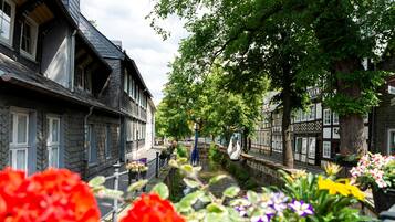 Une rue étroite bordée de bâtiments traditionnels à colombages, un canal et des trottoirs ornés de fleurs.