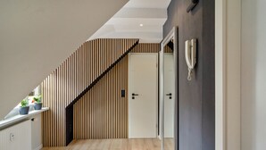 Un intérieur moderne avec un mur à lattes de bois, une porte blanche et une cloison vitrée.