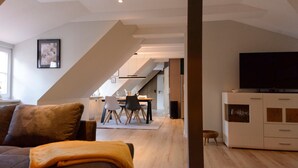Un salon moderne comprenant un canapé, un téléviseur et un coin repas avec des chaises et une table.