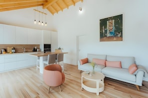 Une cuisine moderne avec des armoires blanches, un plafond en bois et des luminaires suspendus.