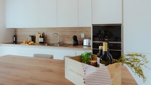 Eine moderne Küche mit weißen Schränken, einer Holz Arbeitsplatte, einem Einbauofen und einem Weinkühlschrank.