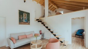 Ein modernes Wohnzimmer mit Treppe, Sofa, Couchtisch und Sessel.