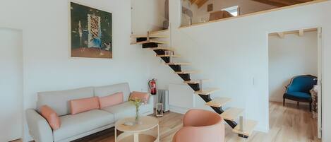 Una sala de estar moderna con una escalera, un sofá, una mesa de centro y una silla.