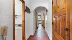 A narrow hallway with wooden doors and a tiled floor.
