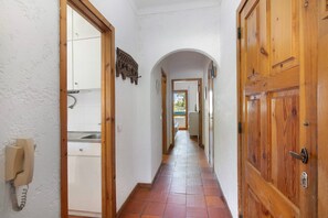 Un pasillo estrecho con puertas de madera y suelo de baldosas.
