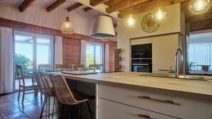 Una cocina moderna con una isla grande, taburetes de bar e iluminación colgante.