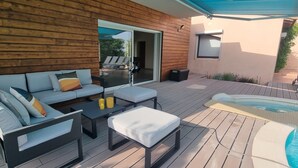 Terraza exterior con sofá, mesa de centro y jacuzzi.