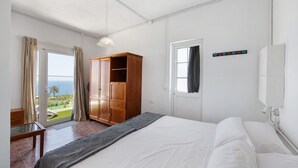 Een slaapkamer met een bed, een houten garderobe, een raam met gordijnen en uitzicht op de omgeving.