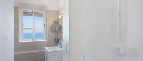 Un bany amb finestra, un lavabo, un mirall i una barra de tovalloles.