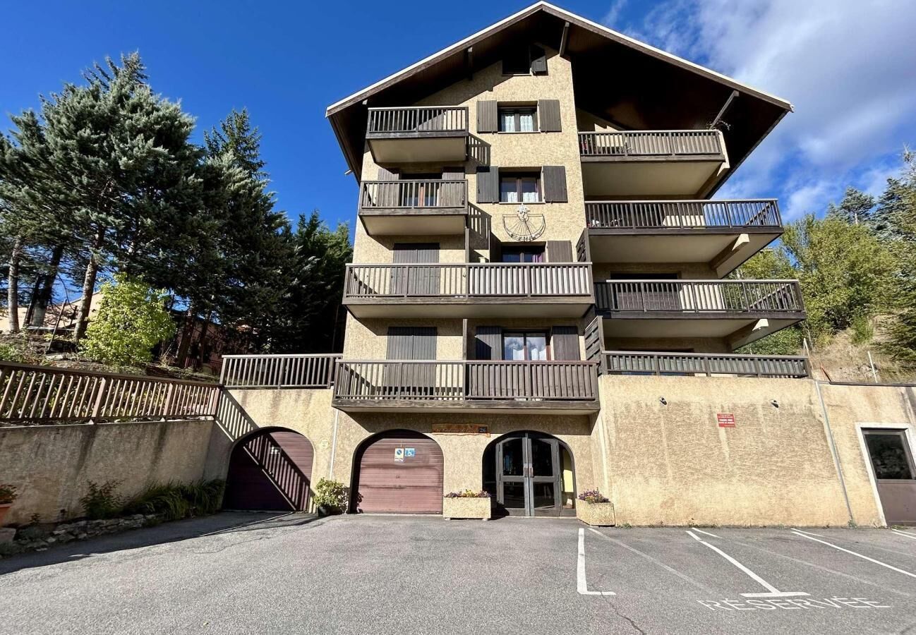 A multi-story building with balconies, a garage entrance, and a parking area.
