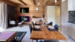 A wooden dining area with a long table set for six, a television, and a fireplace. - 2nd floor, view panoramic, balcony, tv, 45m², Serre Chevalier (Briançon)