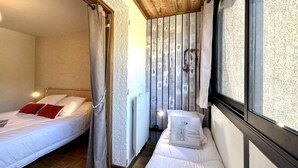 A bedroom with two beds, wooden ceiling, and a window with curtains. - 2nd floor, view panoramic, balcony, tv, 45m², Serre Chevalier (Briançon)