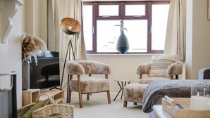 A cozy living room with two plush armchairs, a small coffee table, a floor lamp, and a TV.