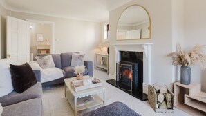 A cozy living room with a fireplace, a sofa, a coffee table, and a mirror.