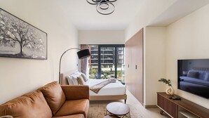 A modern hotel room with a sofa, a bed, a TV, and a view of the city. - FIRST CLASS | Studio | Urban Elegance (Dubai)