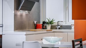 Une cuisine moderne équipée d’un four encastré, d’une machine à café et d’une plante en pot posée sur le plan de travail.
