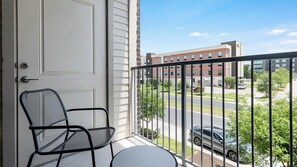 Ein Balkon mit einer weißen Tür, einem Metallstuhl und einem Tisch.