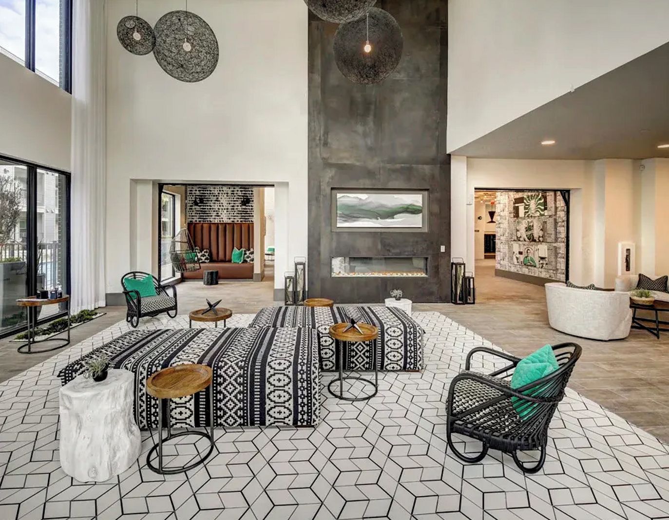 A spacious lobby with a high ceiling, patterned floor tiles, and a central seating area with a fireplace.