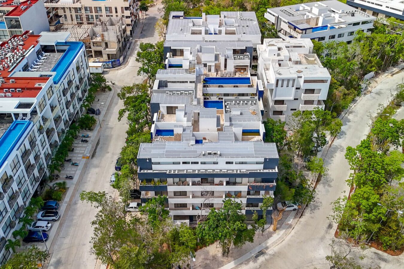 Un immeuble à plusieurs étages, doté d’un toit plat, entouré de verdure et comprenant un espace de stationnement.