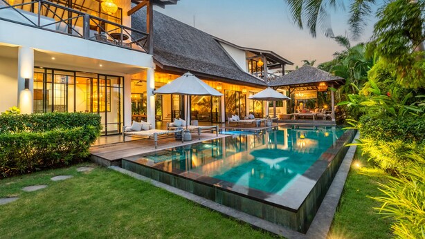 Een modern resort met een zwembad, terras en weelderige beplanting.