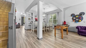 Un vaste espace de vie comprenant une table de baby-foot, un canapé violet et une grande fenêtre.