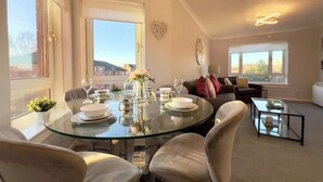 Un espace repas avec une table en verre, des chaises et une vue sur la ville.