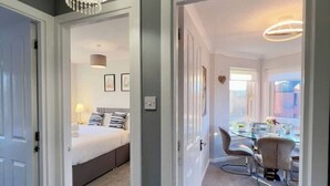 Une chambre à coucher moderne avec un lit, une table de chevet et une lampe. On y trouve également un coin repas avec une table et des chaises.
