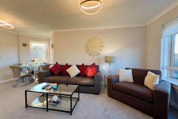 A living room with a sofa, coffee table, and a clock on the wall.