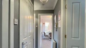 Un couloir avec des portes blanches, un radiateur et, au fond, un coin repas.