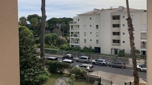 Un edificio residencial de varios pisos con balcones, rodeado de vegetación y coches estacionados.