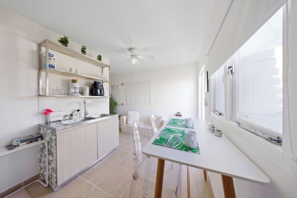 Une cuisine moderne avec un coin repas, des meubles blancs et un ventilateur de plafond.