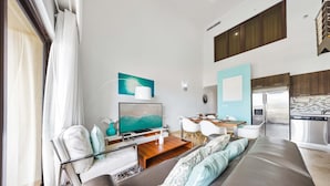 A modern living room with a sofa, TV, and dining area.