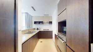 Een moderne keuken met houten kastjes, een roestvrijstalen spoelbak, een inbouwoven en een magnetron.