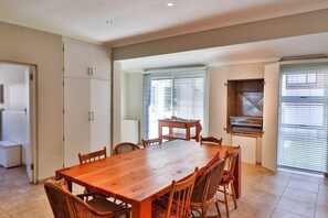 A dining area with a wooden table and chairs, a kitchen with a built-in oven, and a sliding glass door leading to a balcony.