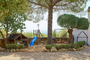 A playground with a slide, swings, and a small wooden structure.