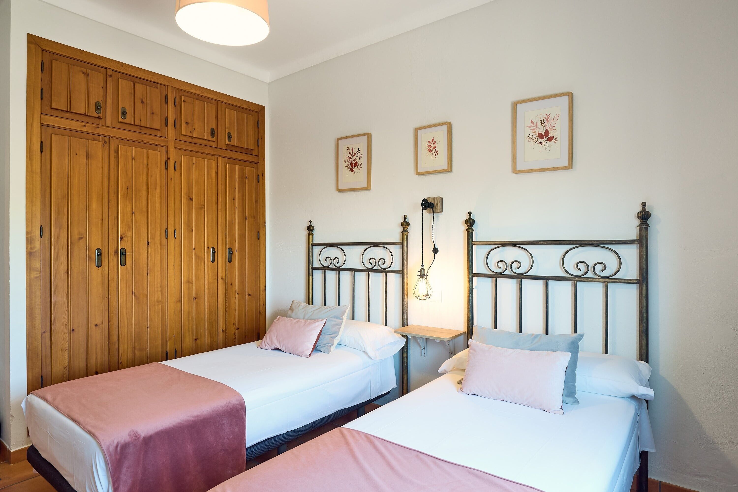 Habitación con dos camas, armario de madera y una obra de arte en la pared.