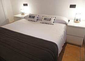 Una cama bien hecha con dos almohadas, una con la palabra 'DREAM' y la otra con 'HELLO'.