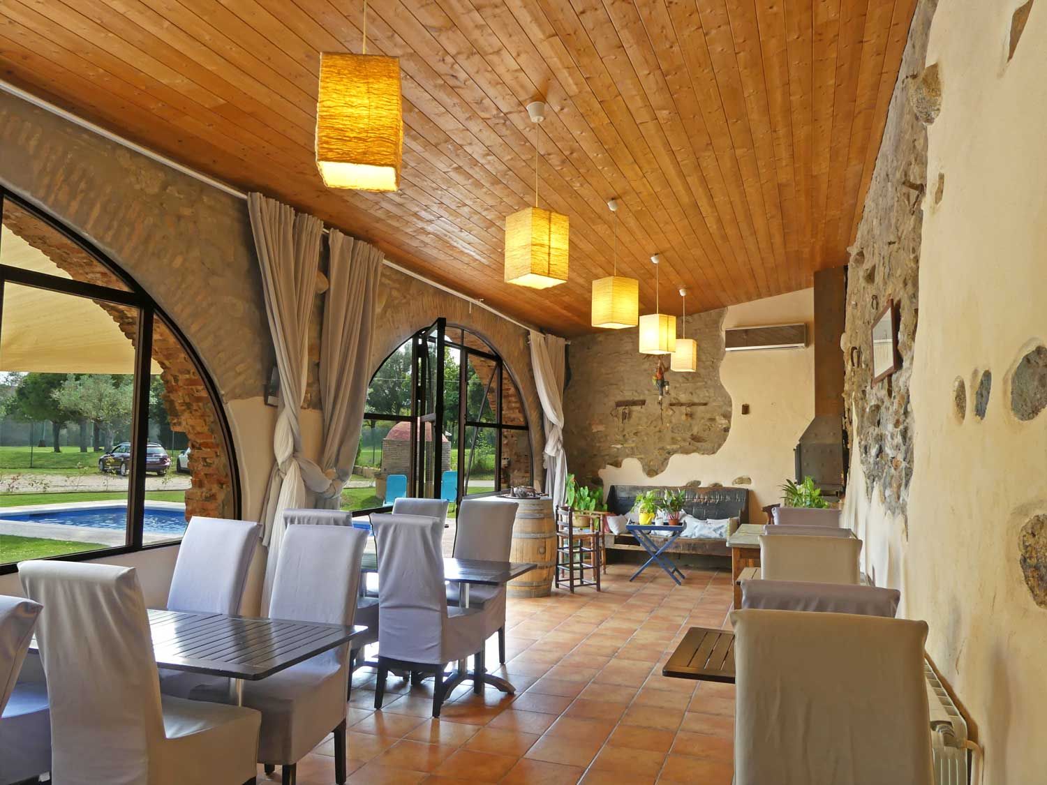 Un comedor rústico con techo de madera, ventanas grandes y vistas al exterior.