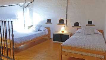 Un dormitori acollidor amb dos llits de fusta, una tauleta de nit amb una làmpada i un disseny de paret rústic.