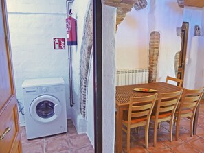Une petite pièce comprenant un lave-linge, une table avec des chaises et un extincteur.