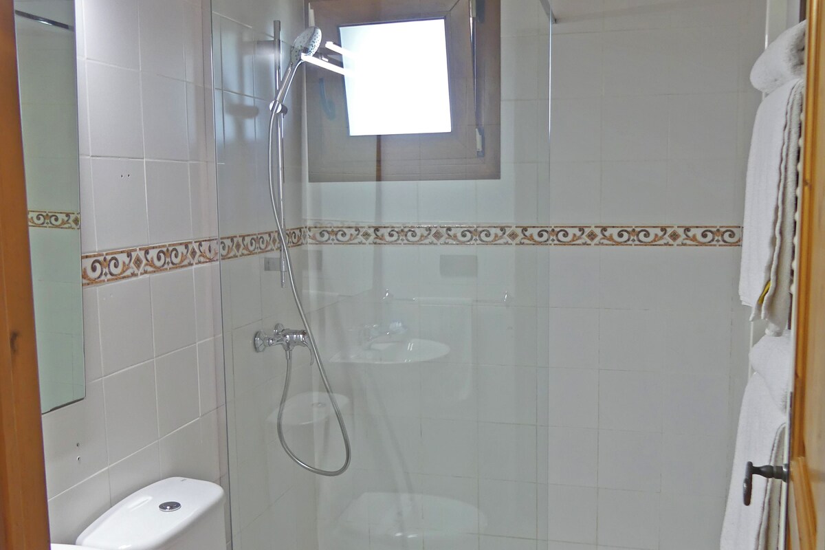 Een badkamer met toilet, wastafel, douche en een klein raam.